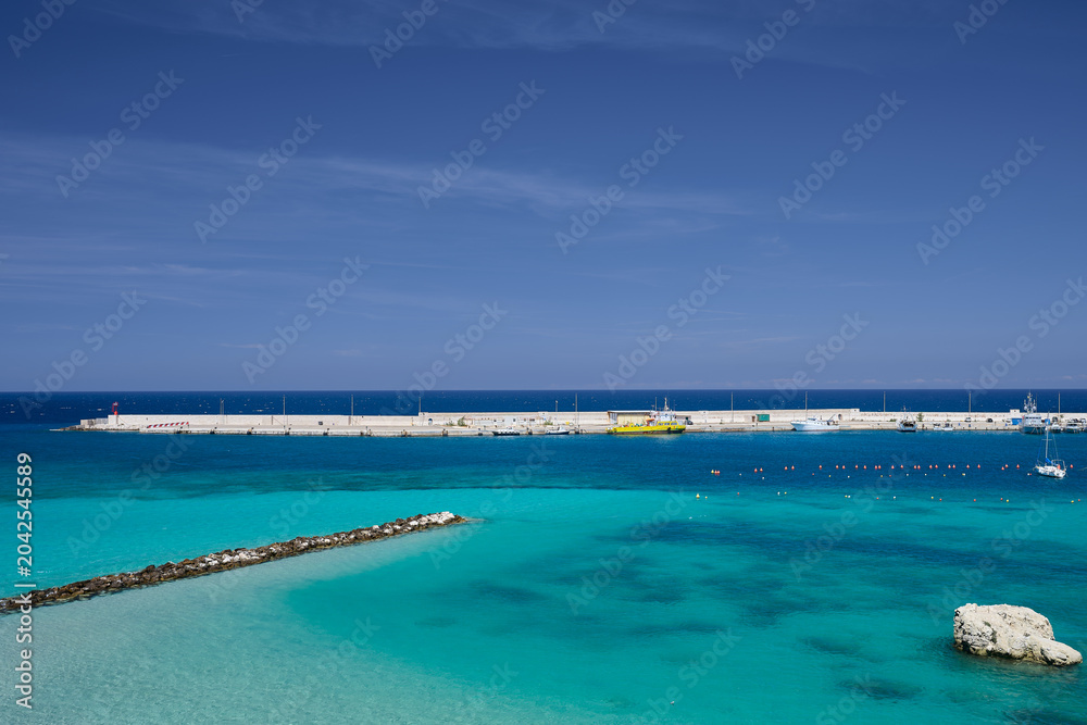 Fototapeta premium Harbour wall \harbor wall in Puglia southern italy with single yacht turquoise sea and blue sky in summer