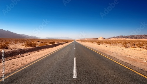 long empty road in desert landscape under clear blue sky