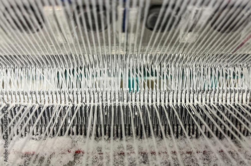 Close-up view of the threads, needles and guide needles of a knitting machine
