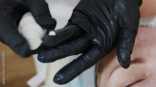 A female doctor, a professional cosmetologist, applies facial ointment to her gloves