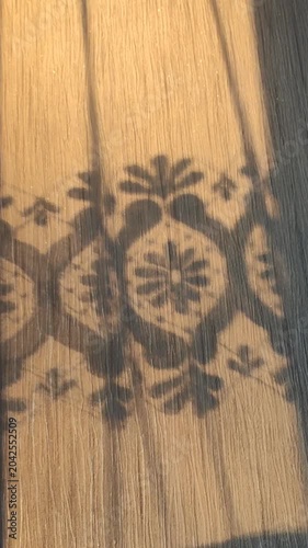 Romantic play of light and shadow formed by a vintage lace curtain illuminated by warm sunlight.