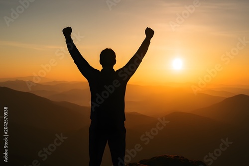 Silhouette of a person with raised arms standing on a mountain peak