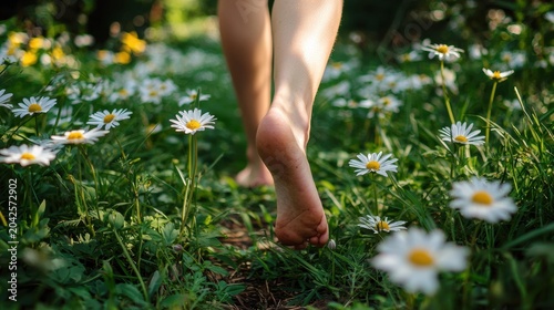 Bare feet walk through a field of white daisies and green grass bathed in sunlight. AI.