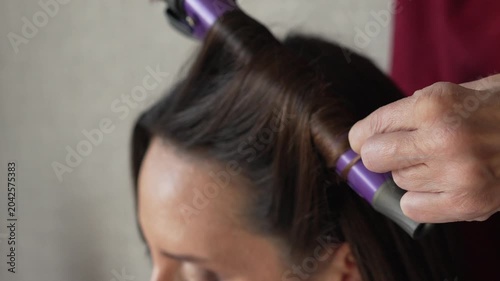 Hair styling woman beauty, professional using curling iron on dark hair, female client getting ready for elegant look
