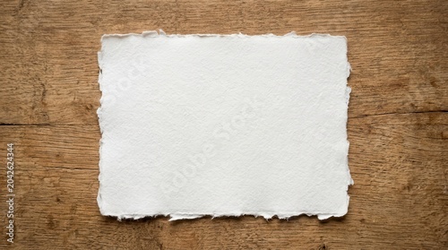 An empty border frame of old torn parchment paper with a rough grunge texture on a vintage brown wood background