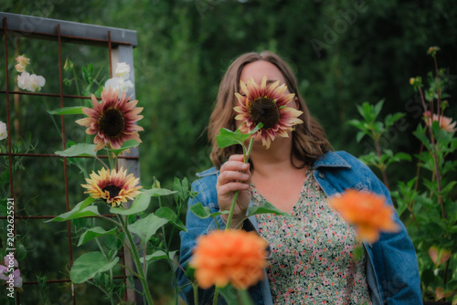 Woman hiding face behind a blooming dark red sunflower