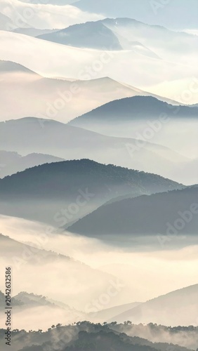 Misty mountain layers at dawn, a serene and breathtaking view of nature's beauty unfolding across the expansive landscape with soft, atmospheric light