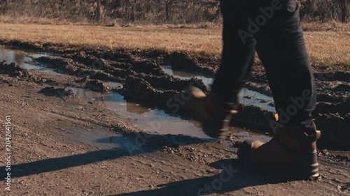 Hiker walking through muddy puddles on a dirt road