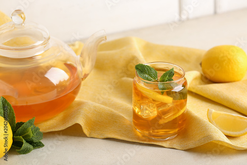 Fotografie Glass and teapot of lemon ice tea with mint on white background, closeup
