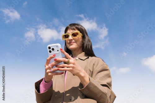 Bright spring day with a young woman using her phone outdoors