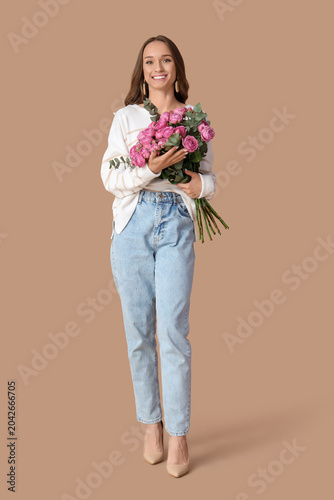 Beautiful young woman with roses on brown background