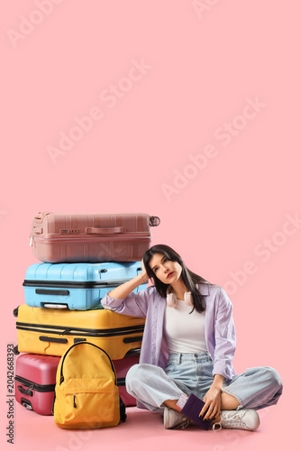 Beautiful young thoughtful female tourist with suitcases, ticket and passport...