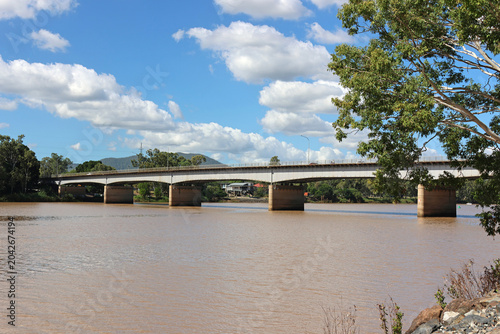 The Fitzroy River Bridge crossing brown river water under a blue sky with scattered clouds in Rockhampton, Queensland, Australia