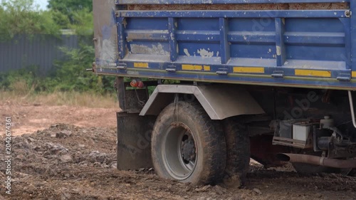Heavy duty commercial truck tires on a dirty, muddy ground at an industrial worksite.
