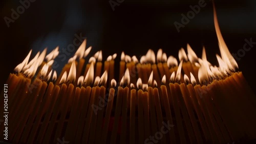 Rows of warm candle flames in a dark temple setting create a sacred visual composition with glowing light, soft smoke, and peaceful Buddhist worship atmosphere.