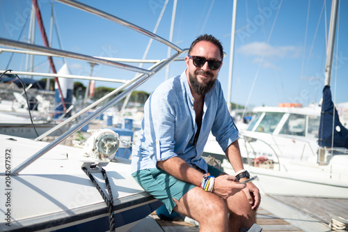 Man enjoying summer vacation on a sailboat in marina