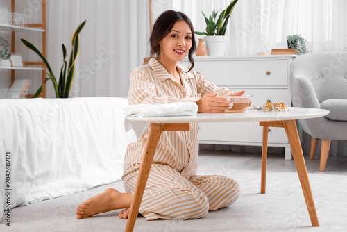 Foto Young Asian woman preparing steam inhalation at table in bedroom