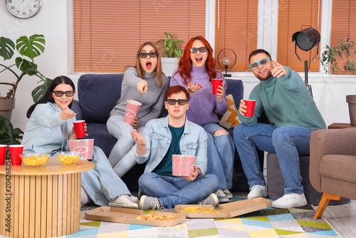 Group of young friends in 3D glasses with beer and popcorn watching movie at ...
