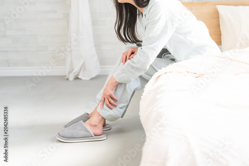 Plakat 起きてベッドの上で膝の痛みを訴えている女性