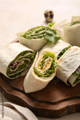 Konstfotografi Wooden board of tasty lavash rolls with onion, egg and greens on light backgroun