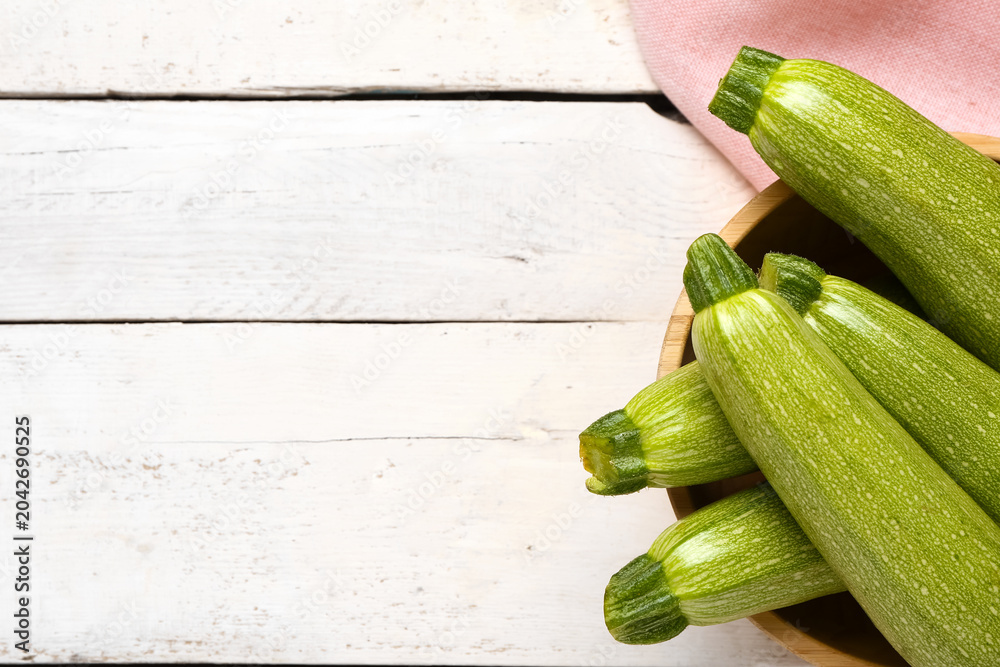 Obraz premium Bowl with many fresh green zucchini on white wooden background