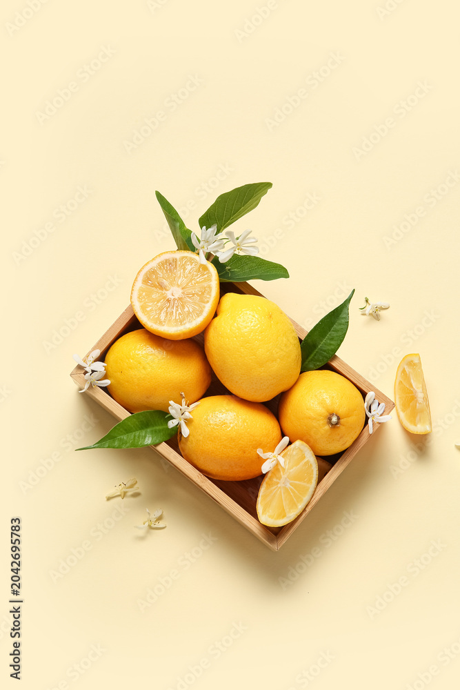Obraz premium Wooden box of lemons with blooming branch on beige background