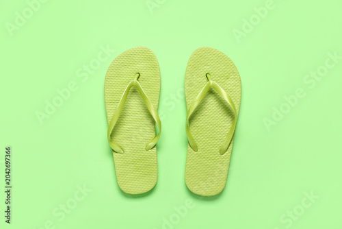 Fotografía Flip-flops on green background, top view