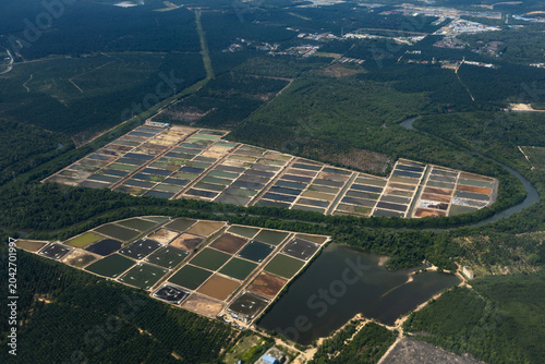 Aerial view of aquaculture ponds and farming facilities surrounded by mangroves and plantation land on the outskirts of Kuala Lumpur, Malaysia.
