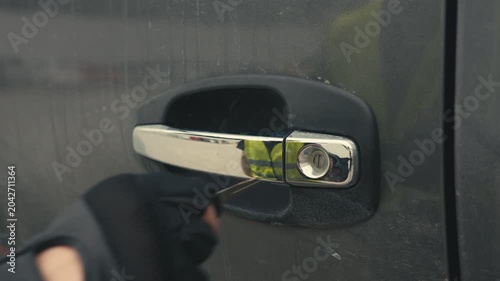 Criminal in black gloves breaking into a car
