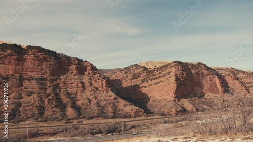 Cars driving on a highway through a scenic red rock canyon in utah