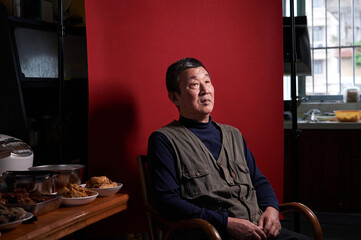 A middle-aged Chinese man at home with a red background