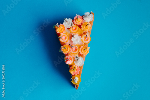 a cake slice holds extinguished candles in flower-shaped holders