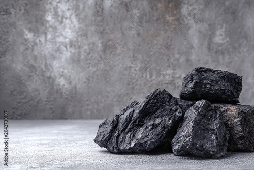 Stack of coal against textured grey background, studio shot, close-up on table surface