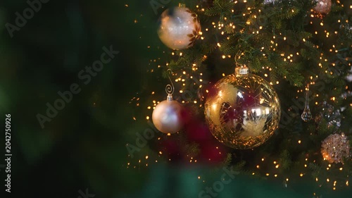 Vintage, gold Christmas ornaments hanging on a decorated Christmas tree. Sparkling golden lights. Christmas background.