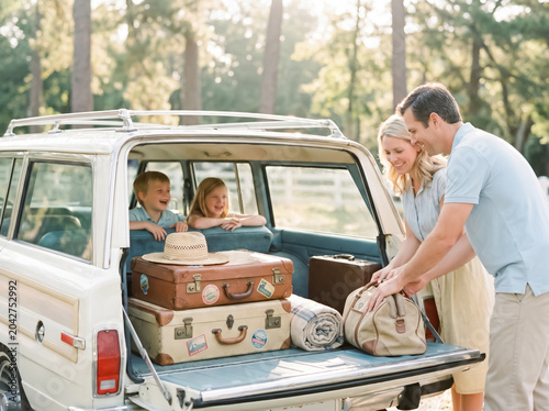 Parents packing vintage luggage into their classic station wagon