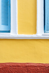 Yellow wall with blue shutters and red base 