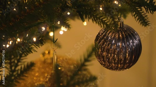 Silver Christmas ornament hanging off the branch of a decorated Christmas tree. Christmas background. 