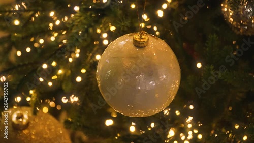 Decorated Christmas tree with white ornaments and golden, glowing Christmas lights. Christmas background.