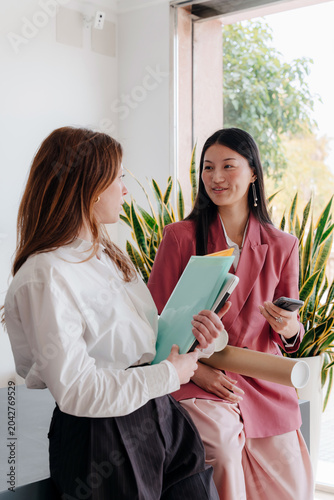 Young professional women at work having a conversation inside office