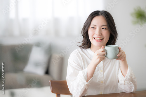 Foto 朝のくつろぐ時間にマグカップを持つ笑顔の女性ライフスタイル上半身