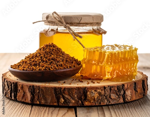 A honeycomb and honey jar on a wooden platter with pollen