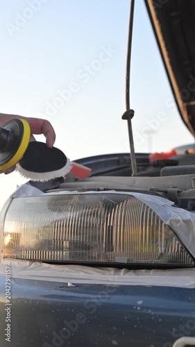 The process of polishing car headlights outdoors. 