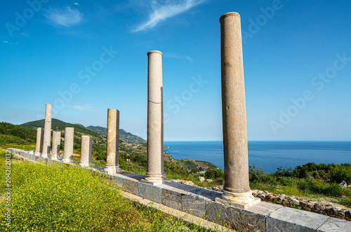 Scenic landscape of the archaeological ruins of Antiochia ad Cragum with ancient columns and stone walls perched on a high cliff overlooking the deep blue Mediterranean Sea in Gazipasa, Turkey.