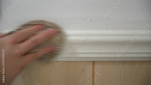 Closeup of a man's hand wiping a dirty white wall with a wet, soapy towel. Household tasks. Daily chores. Spring cleaning. Tidy home.