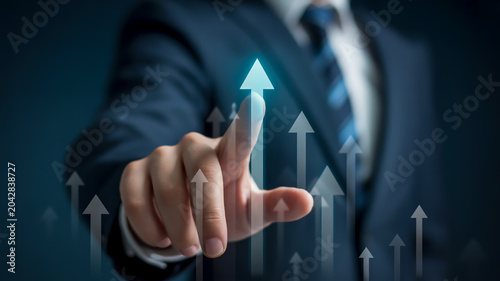Upward trending arrow held by hand against blue background with graph lines finger