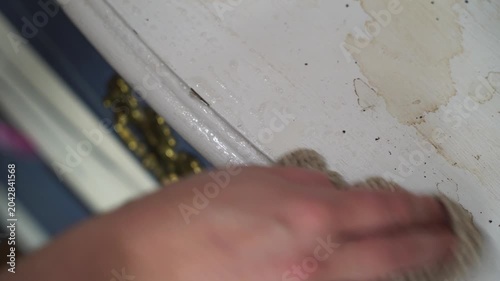Man scrubs dirt, grime, and stains off a white wood surface. White towel and soap. Housework. Chores. Cleaning the home. Removing stains.