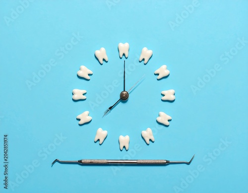 A dental-themed composition featuring a clock face made of teeth with a dental tool beneath on a bright blue background