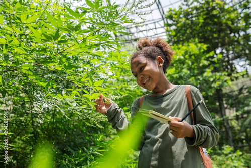 Fotografie Young Student Discovering Tropical Plant Diversity in a Living Insect Dome