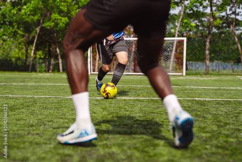 Foto Soccer player dribbling yellow ball against defender on turf field