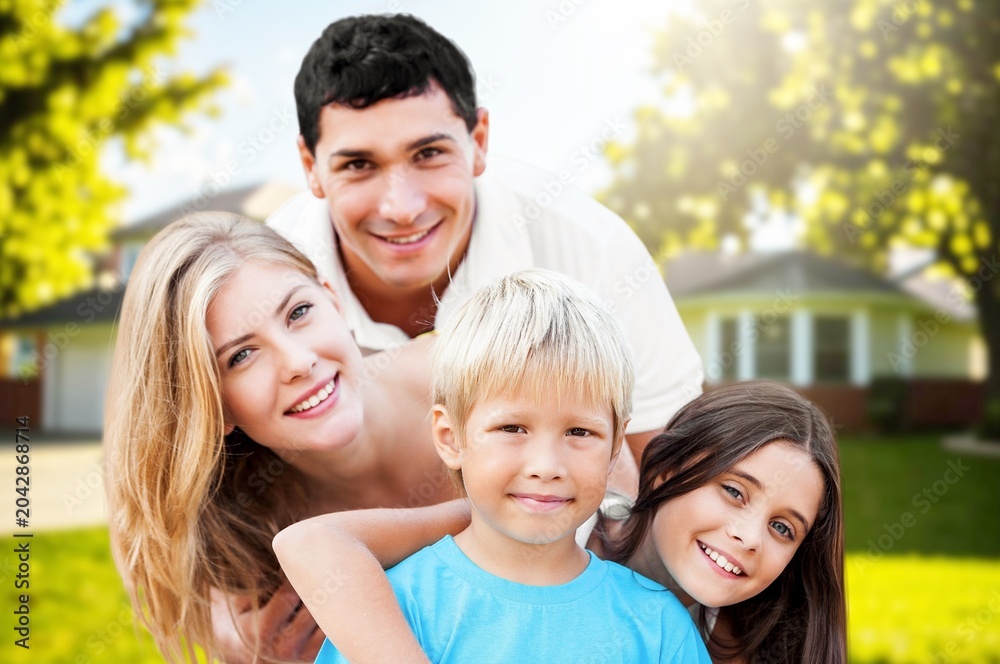 Fototapeta premium Happy family with children smiling in front of their new home on a sunny day
